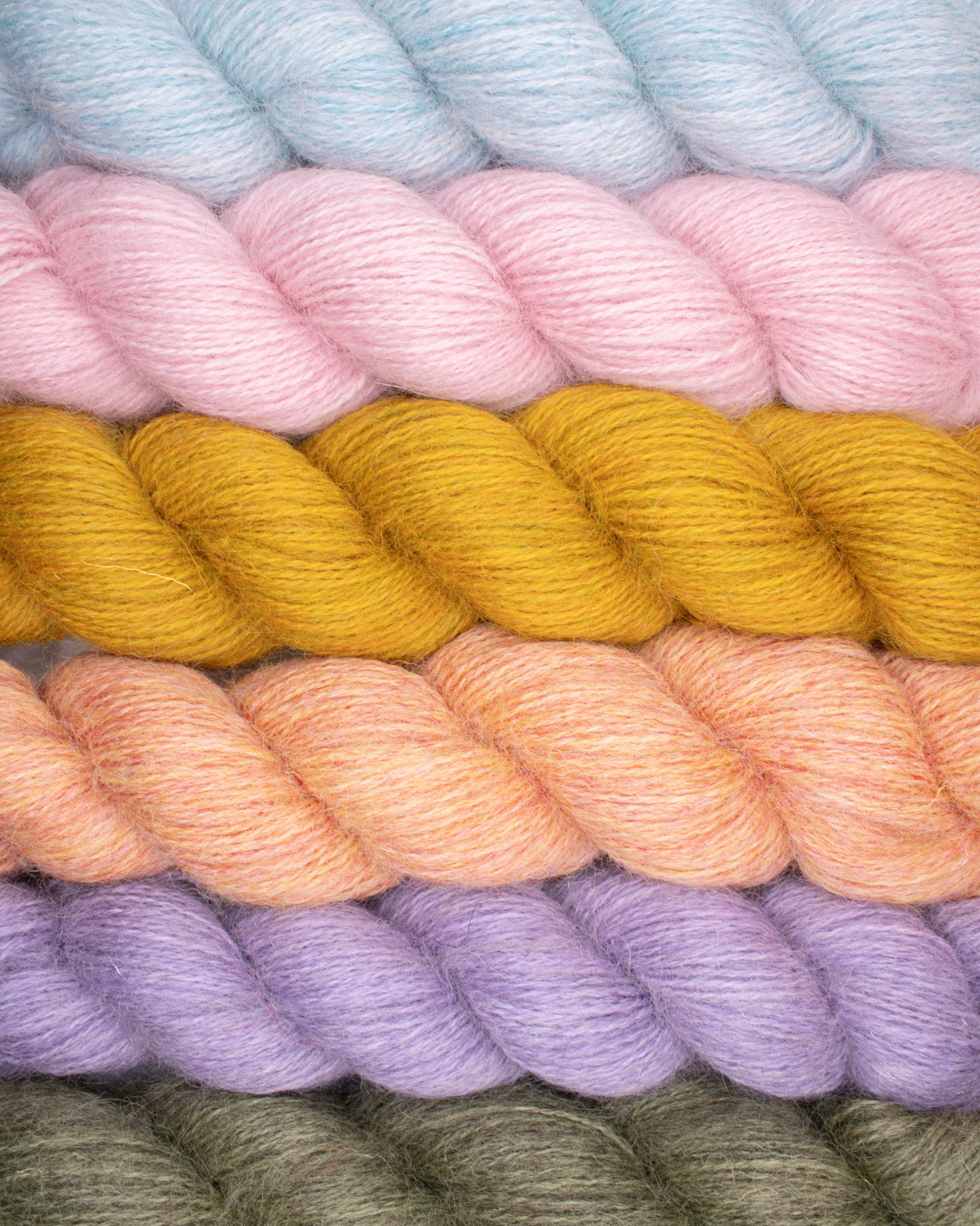 Soft, natural Mowool yarn by Baa Ram Ewe in various colors, showcasing its cozy, textured wool fibers for knitting and weaving.