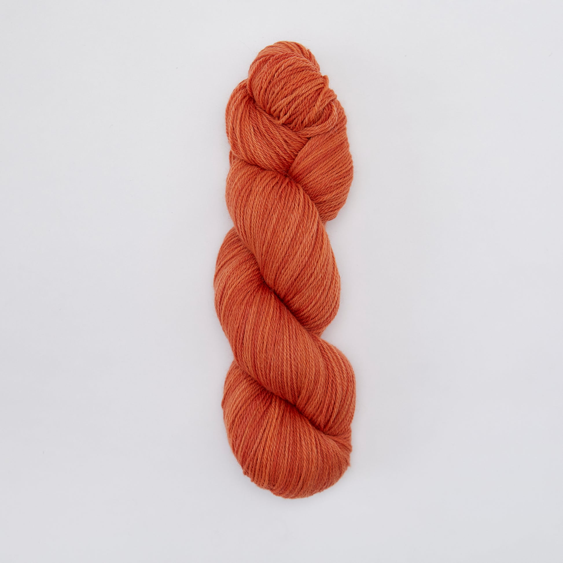 Kinua The Fingering Luxury Blend yarn in pumpkin orange, showing soft, textured fiber suitable for knitting or crochet projects.