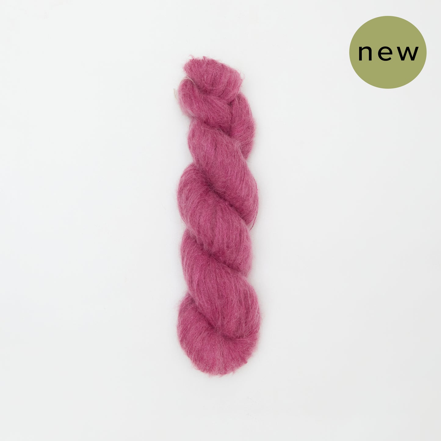 Soft pink Kinua The Fuzzy yarn in a ball, showcasing its fuzzy texture and vibrant color for cozy knitting projects.