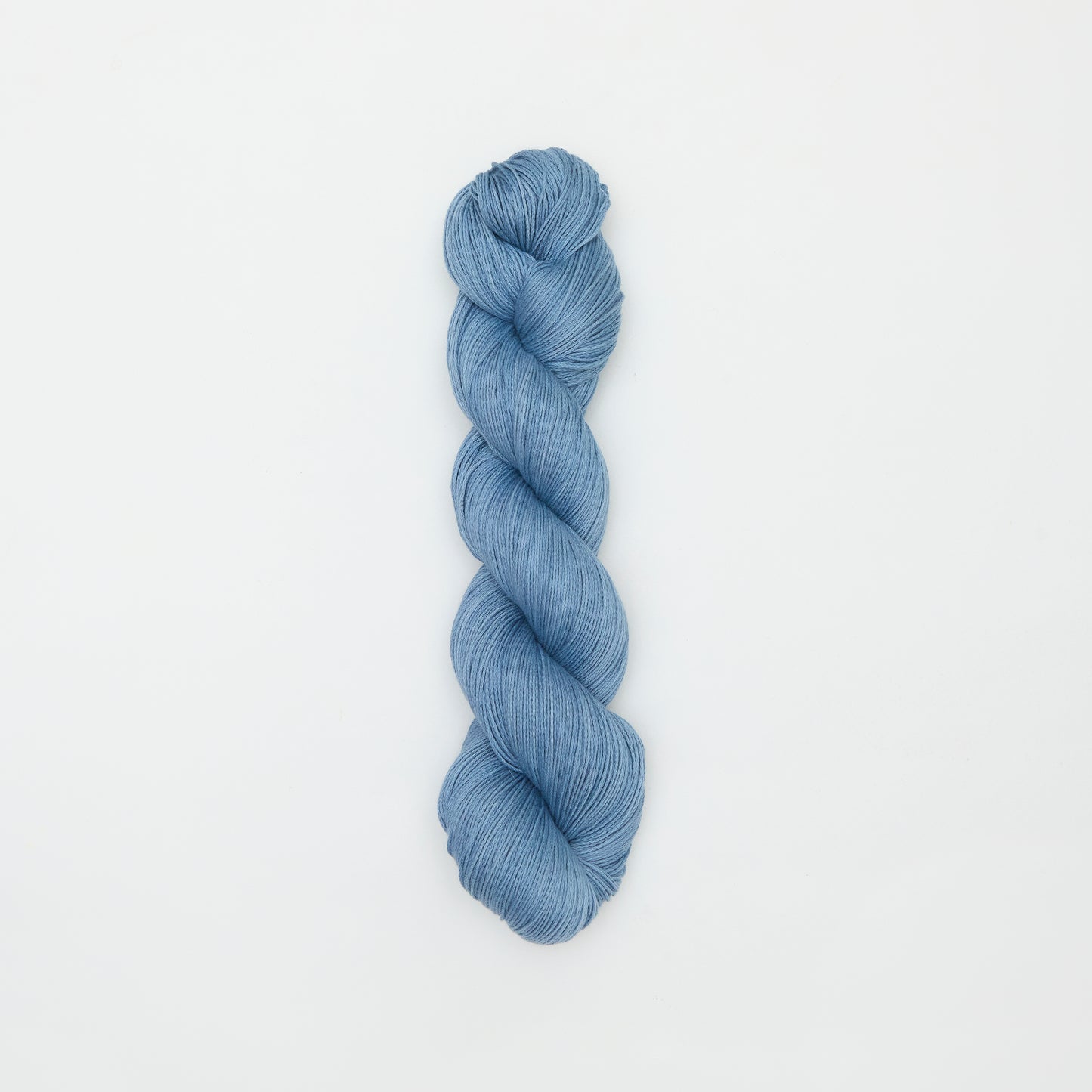 Blue sky-colored organic cotton yarn from Kinua's The Fingering collection, showing soft, twisted fibers ready for knitting or crochet.