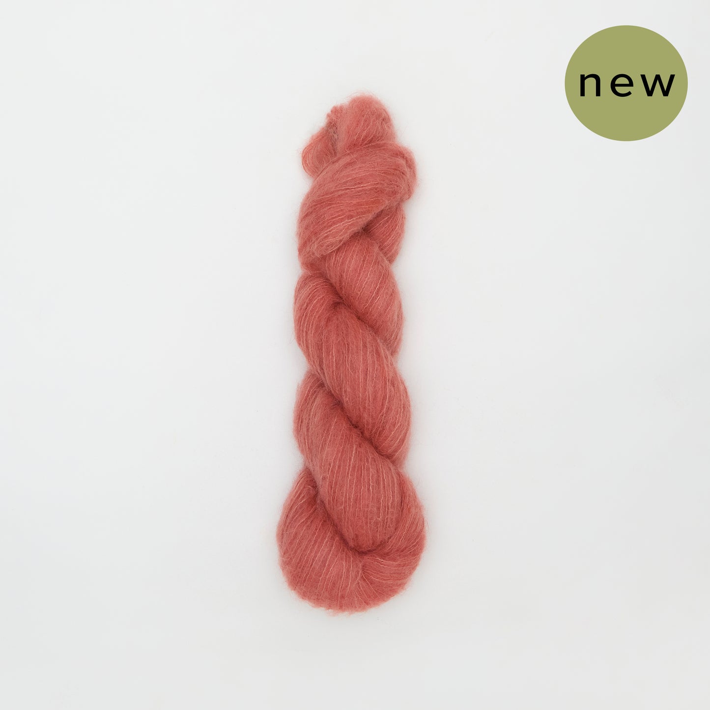 Coral-colored Kinua The Fuzzy yarn ball, soft and textured, ideal for knitting or crocheting projects.